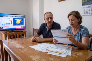 Pareja sentada a la mesa del salón revisando documentos sobre la solicitud del bono social y facturas de telecomunicaciones.