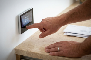 Mano seleccionando la temperatura de 28 grados en la pantalla táctil de un termostato digital inteligente.