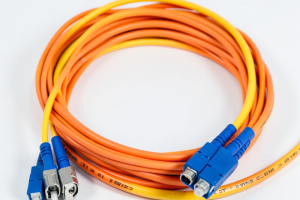 Cable de fibra óptica dúplex enrolado en colores naranja y amarillo con conectores azules en los extremos.