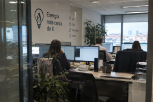 Oficina de VD Energy con empleados trabajando frente a ordenadores y vinilo de Energía más cerca de ti en la pared.